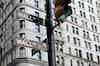A traffic light in downtown NYC with the words Wall ST on the attached street signs.